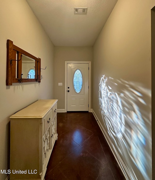 doorway to outside with dark tile patterned flooring and a textured ceiling