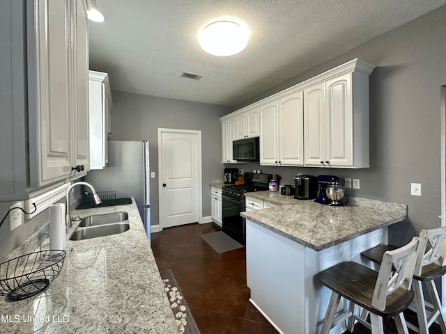 kitchen featuring light stone countertops, sink, a textured ceiling, white cabinets, and black appliances