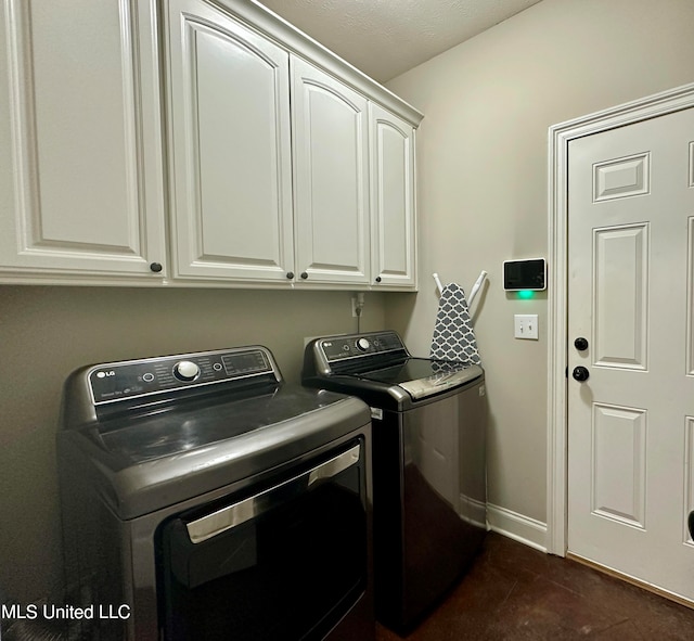 laundry room with washing machine and clothes dryer, cabinets, and dark tile patterned flooring