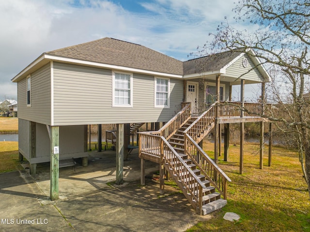 rear view of property with a carport, covered porch, and a lawn