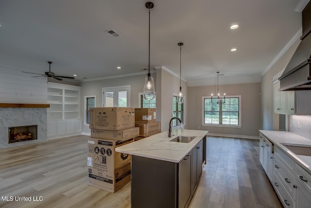 kitchen featuring hanging light fixtures, light stone counters, white cabinetry, light hardwood / wood-style floors, and sink