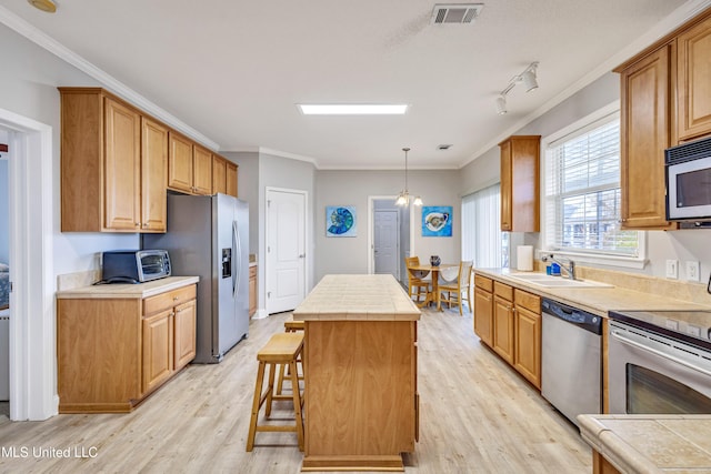 kitchen with sink, light hardwood / wood-style floors, a center island, and appliances with stainless steel finishes