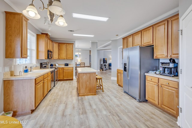 kitchen featuring hanging light fixtures, appliances with stainless steel finishes, a center island, and sink