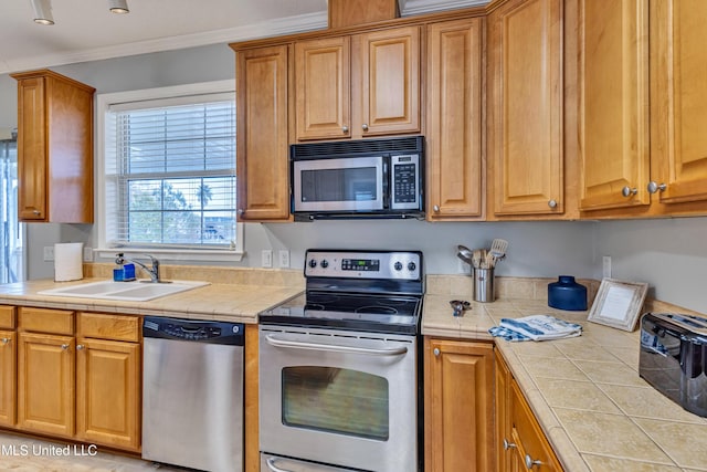 kitchen featuring ornamental molding, appliances with stainless steel finishes, sink, and tile counters