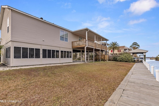 back of house with a gazebo, a sunroom, a deck with water view, and a lawn