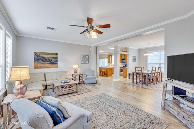 living room with crown molding, ceiling fan with notable chandelier, and light hardwood / wood-style flooring