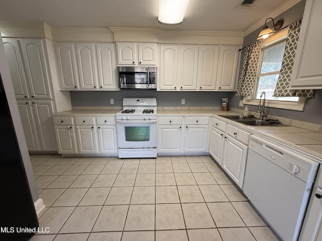 kitchen with white appliances, white cabinets, a sink, and tile countertops