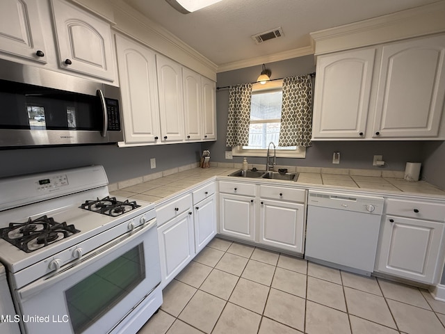 kitchen featuring white appliances, a sink, tile counters, and white cabinetry