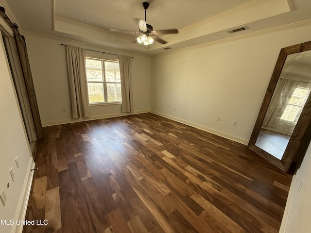 unfurnished bedroom featuring a barn door, baseboards, a raised ceiling, dark wood finished floors, and ornamental molding