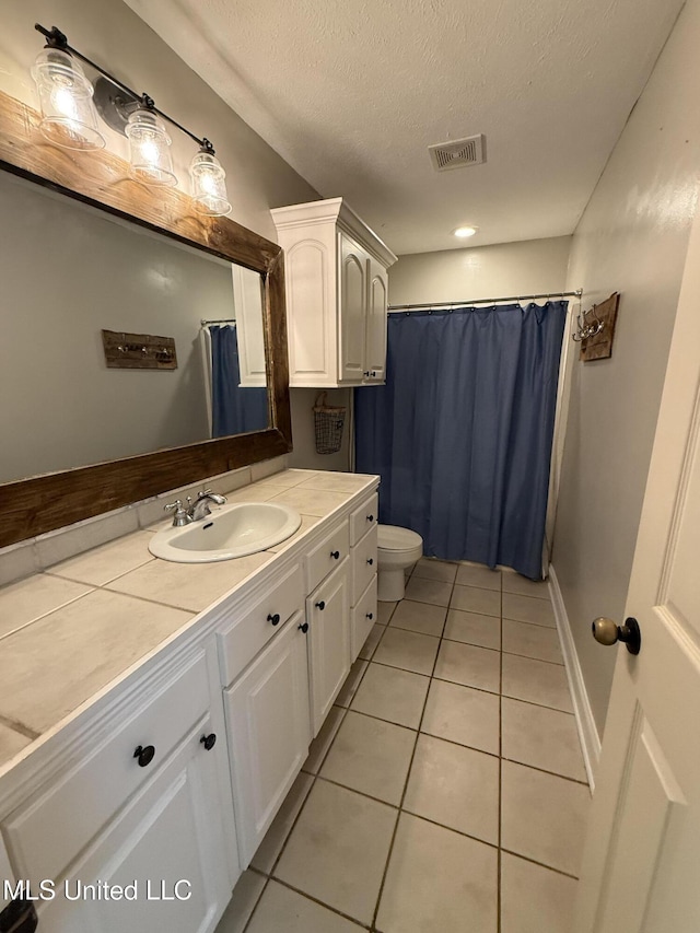 bathroom featuring visible vents, toilet, a textured ceiling, vanity, and tile patterned flooring