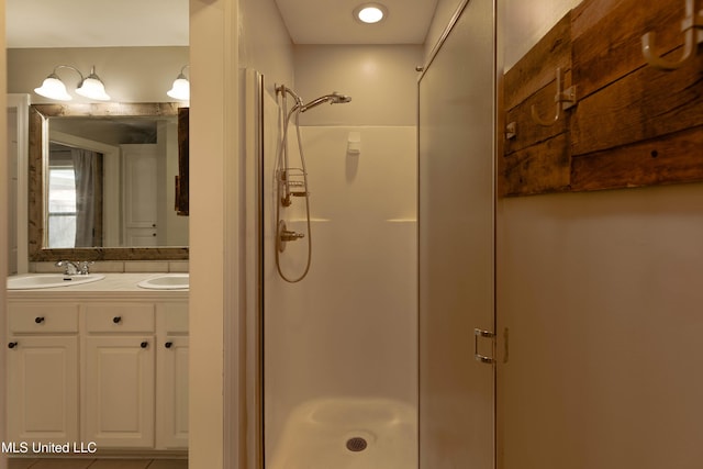 full bath with double vanity, a stall shower, and a sink