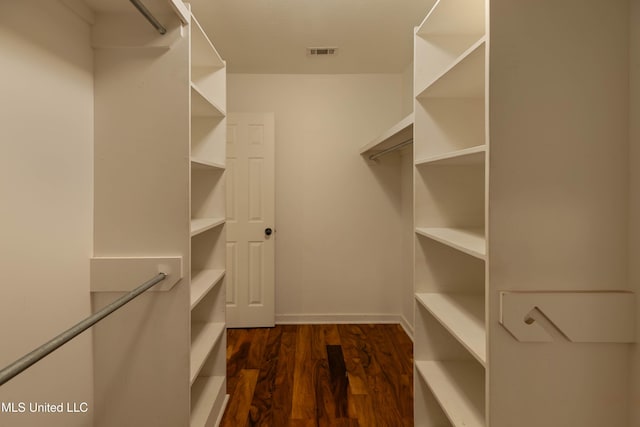 spacious closet with dark wood-style flooring and visible vents