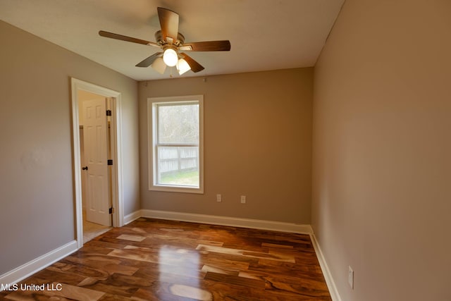 spare room featuring wood finished floors, a ceiling fan, and baseboards