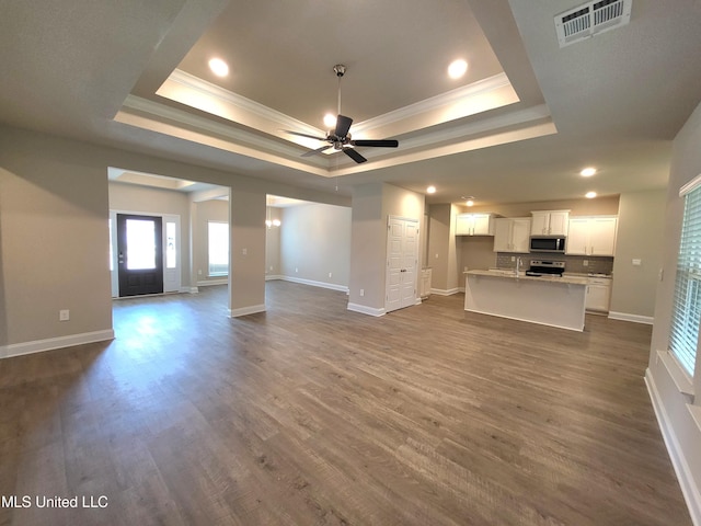 unfurnished living room with visible vents, a tray ceiling, and ornamental molding