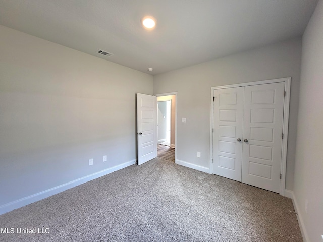 unfurnished bedroom with carpet floors, baseboards, visible vents, and a closet