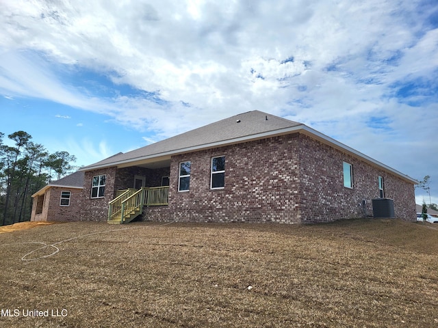 back of property featuring brick siding and central AC