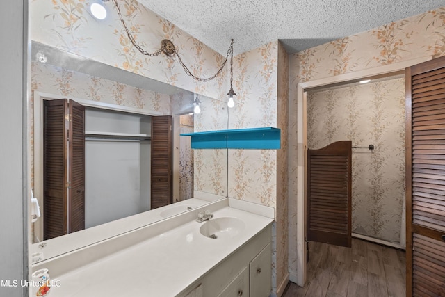 465 Heritage Pl, Jackson, MS 39212 - bathroom featuring wood finished floors, a closet, a textured ceiling, wallpapered walls, and vanity