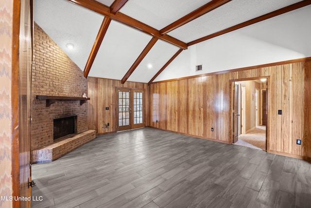 465 Heritage Pl, Jackson, MS 39212 - unfurnished living room with wood walls, beam ceiling, wood finished floors, a brick fireplace, and french doors