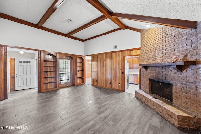 465 Heritage Pl, Jackson, MS 39212 - unfurnished living room featuring beam ceiling, wood finished floors, a fireplace, wooden walls, and a textured ceiling