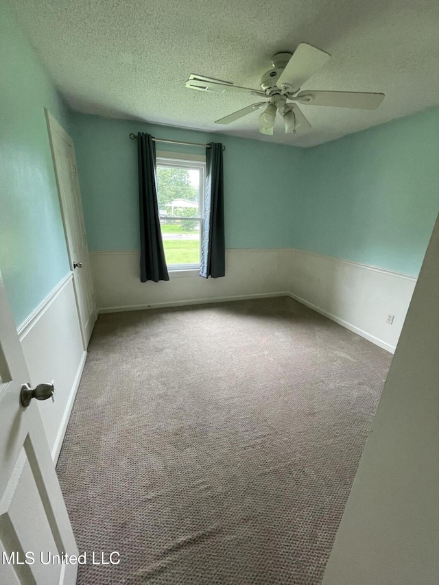 137 Phil Ln, Sardis, MS 38666 - carpeted empty room featuring a ceiling fan, a wainscoted wall, and a textured ceiling