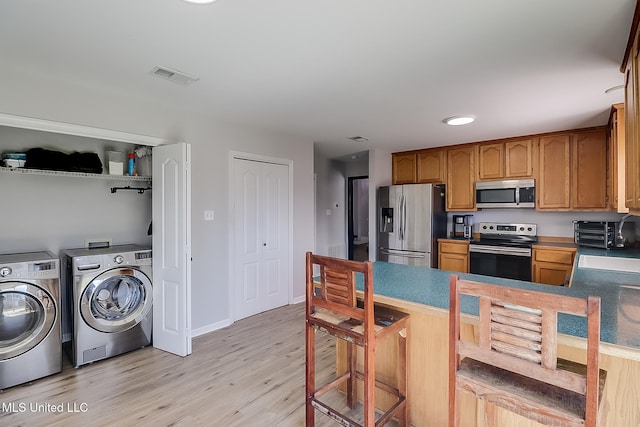 kitchen featuring washer and clothes dryer, stainless steel appliances, dark countertops, visible vents, and brown cabinetry