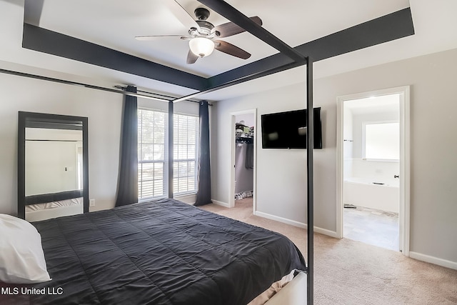 bedroom with a raised ceiling, light colored carpet, a spacious closet, and baseboards