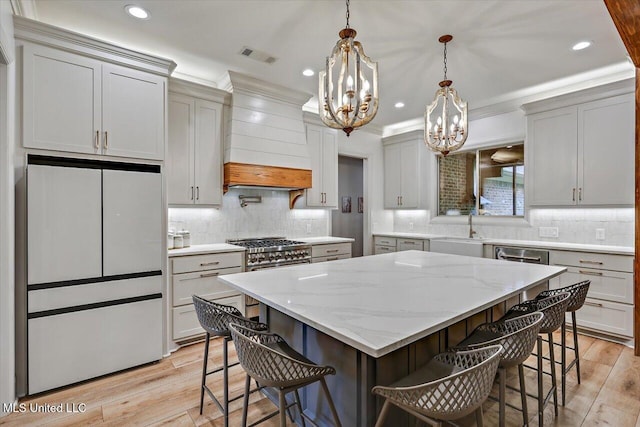 kitchen featuring premium range hood, visible vents, a large island, white fridge, and a kitchen bar