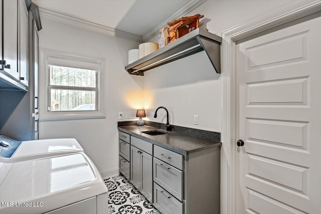 laundry room with a sink, baseboards, cabinet space, washing machine and clothes dryer, and crown molding