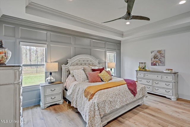 bedroom with crown molding, light wood-style floors, a decorative wall, and a ceiling fan