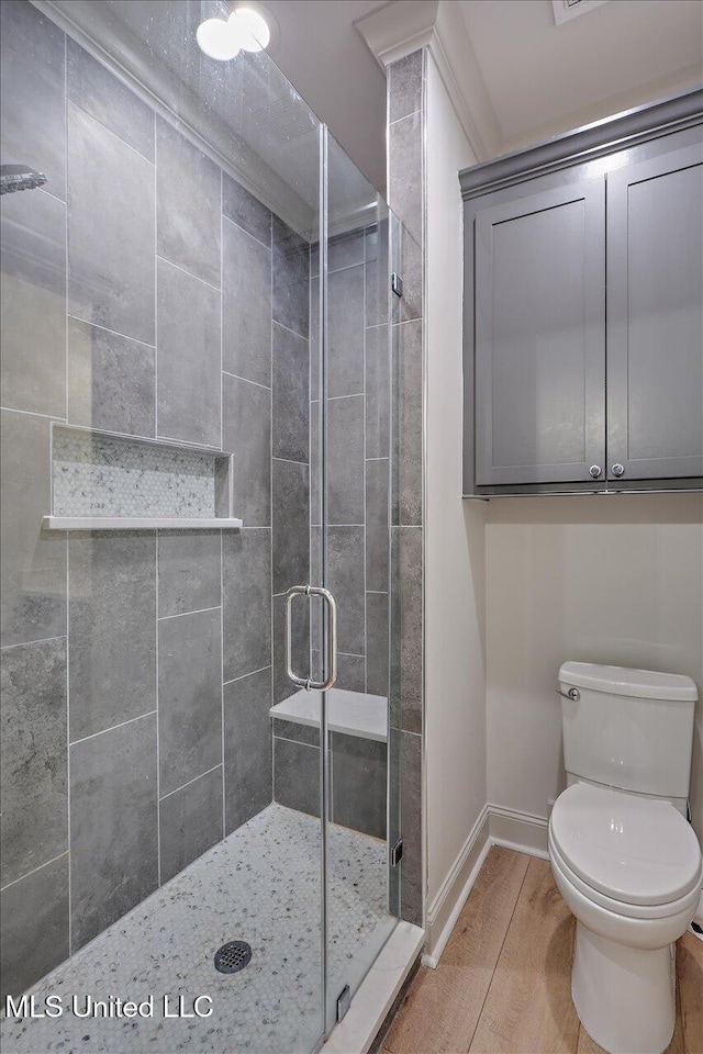 bathroom with a stall shower, toilet, and baseboards