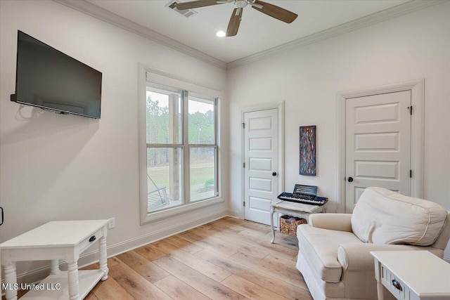 living area featuring light wood finished floors, baseboards, visible vents, a ceiling fan, and crown molding