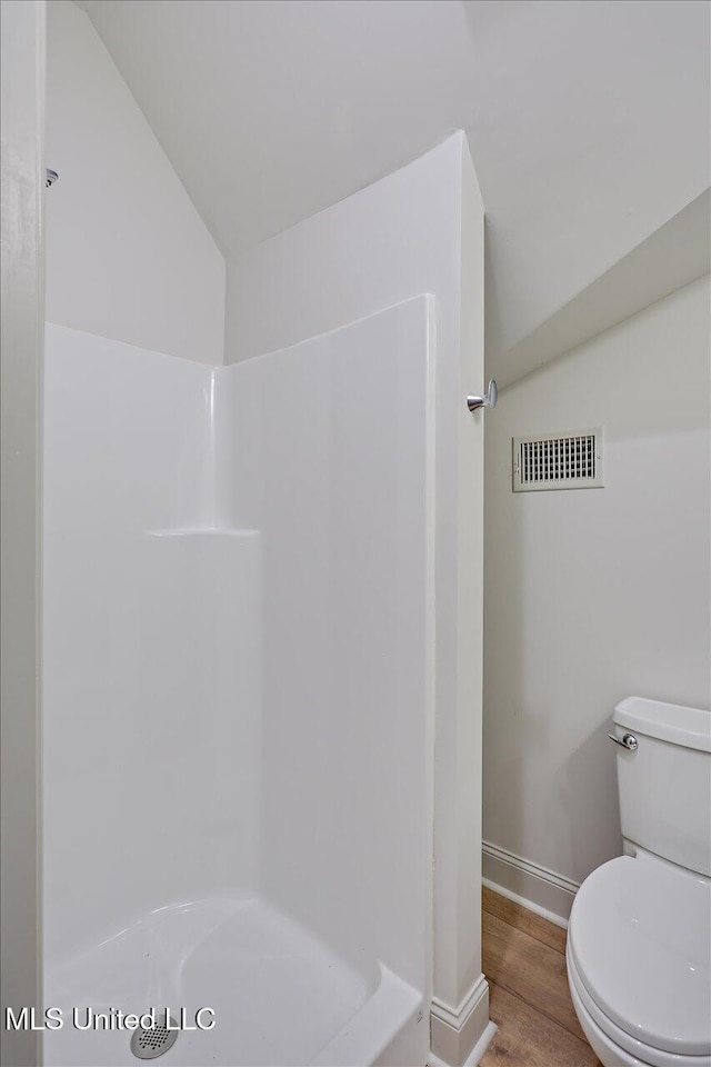 full bathroom featuring visible vents, toilet, wood finished floors, walk in shower, and vaulted ceiling