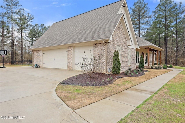 view of side of property featuring brick siding, a porch, a shingled roof, concrete driveway, and a garage