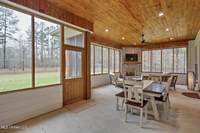 sunroom / solarium featuring ceiling fan, a brick fireplace, and wood ceiling