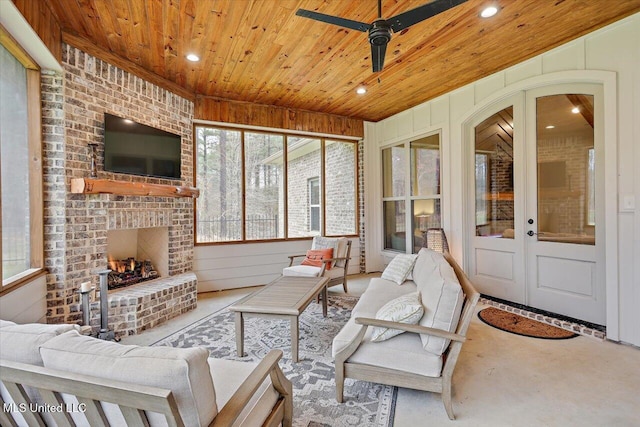 sunroom / solarium with wooden ceiling, an outdoor brick fireplace, a ceiling fan, and a wealth of natural light