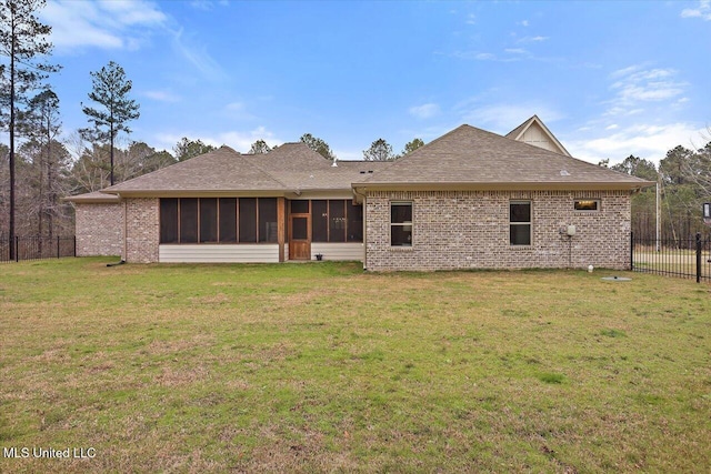 back of property featuring brick siding, a lawn, fence, and a sunroom