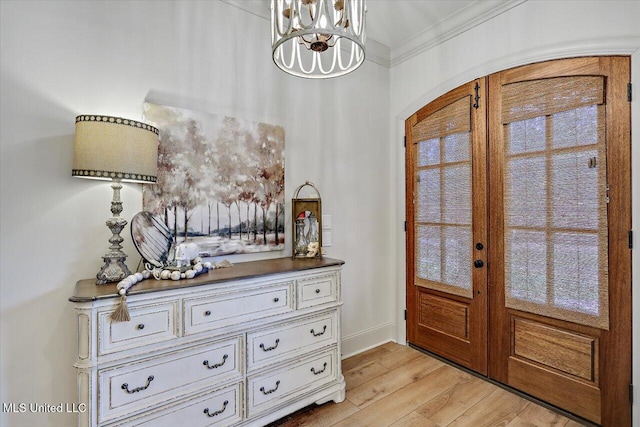 entrance foyer featuring baseboards, crown molding, french doors, light wood-type flooring, and a chandelier