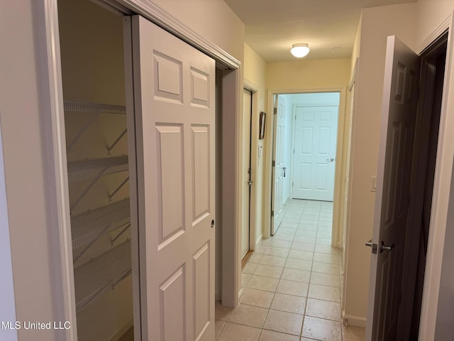 hall featuring light tile patterned floors and baseboards