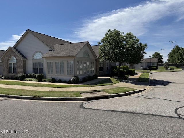 french provincial home with a shingled roof and brick siding