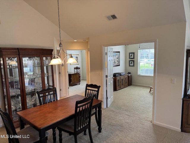 dining area featuring light colored carpet, lofted ceiling, and baseboards