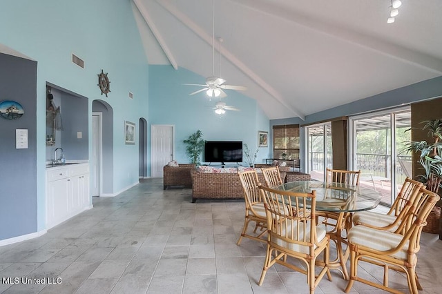 dining room featuring ceiling fan, beam ceiling, sink, and high vaulted ceiling