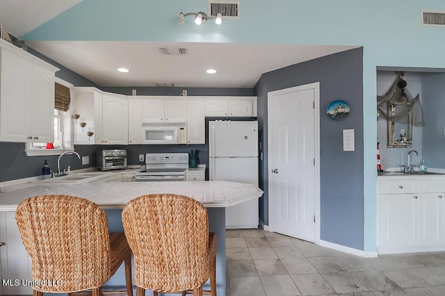 kitchen featuring kitchen peninsula, white cabinetry, sink, and white appliances