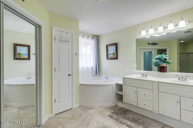 bathroom with a textured ceiling, vanity, and a tub