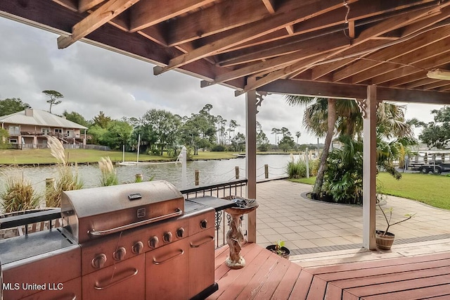 view of dock featuring a yard, a water view, a patio area, and exterior kitchen