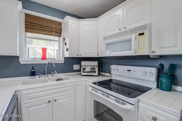 kitchen featuring tile counters, white cabinetry, white appliances, and sink