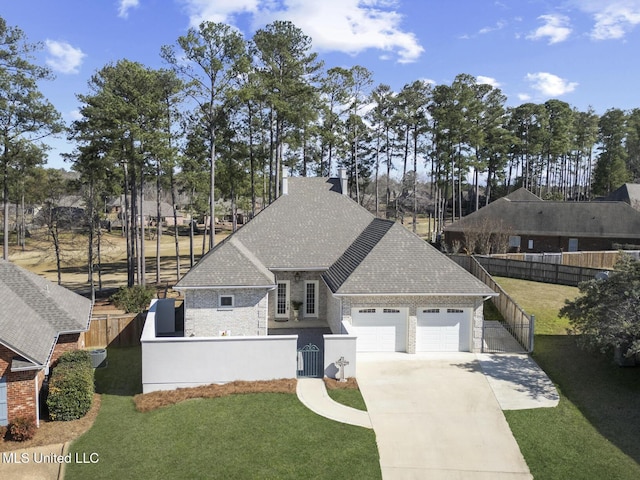 view of front of property with a fenced front yard, roof with shingles, driveway, and an attached garage