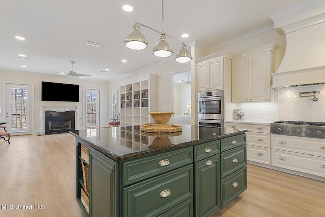 kitchen featuring stainless steel appliances, custom range hood, green cabinets, and crown molding