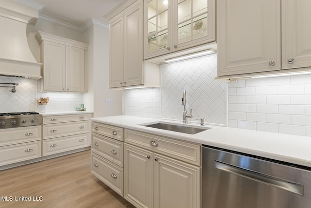 kitchen featuring a sink, light countertops, ornamental molding, appliances with stainless steel finishes, and custom exhaust hood