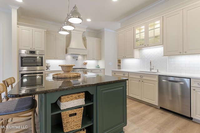 kitchen featuring premium range hood, a sink, appliances with stainless steel finishes, a kitchen bar, and crown molding