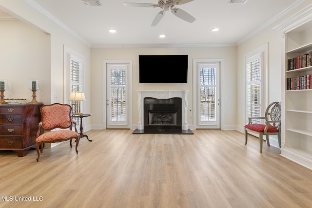 sitting room featuring baseboards, crown molding, light wood finished floors, and a premium fireplace